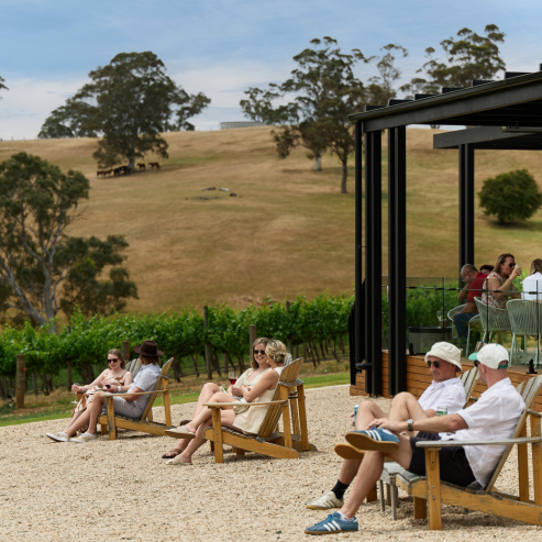 Nepenthe vineyard on a sunny day with people sitting outside on the lawn drinking wine