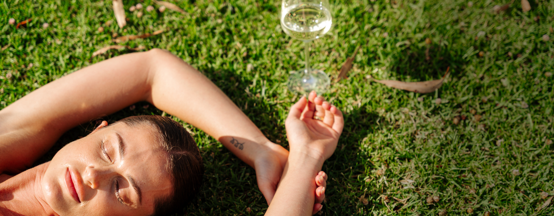 Woman lying on the grass holding glass of wine