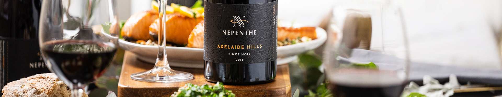 Bottle of Nepenthe Pinnacle with a red wine glass next to it