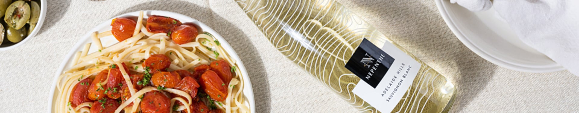 Spring promotion on white wines with Nepenthe Ascend Sauvignon Blanc in an indoor table setting with pasta.